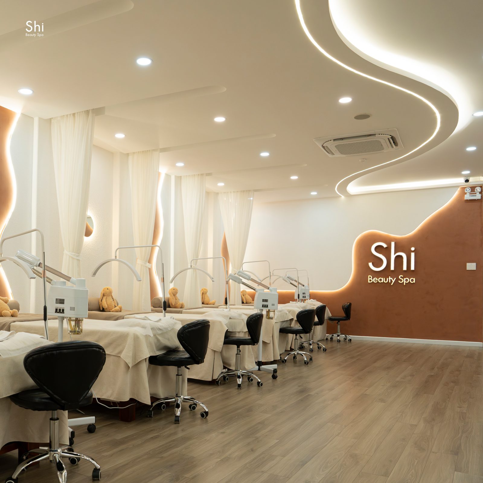 Phòng dịch vụ facial tại Shi, các giường chăm sóc da xếp dọc tường có logo Shi