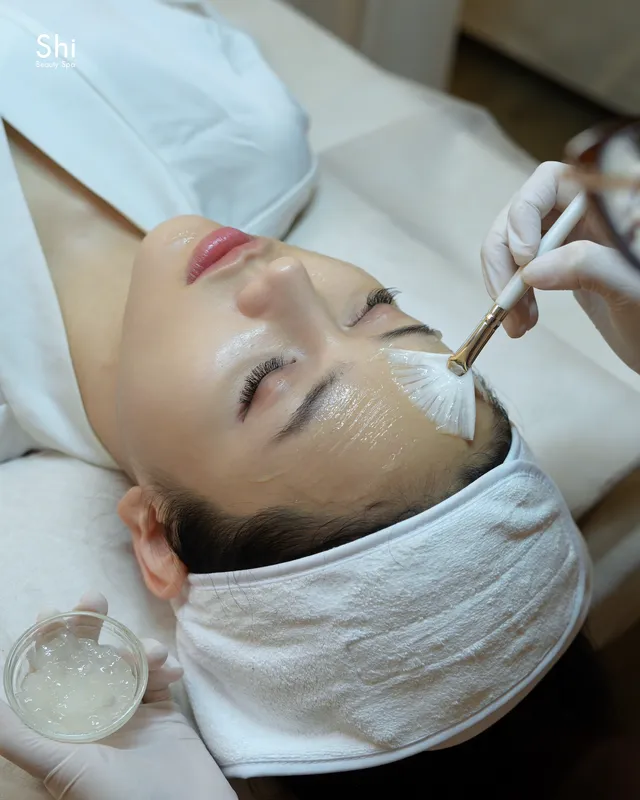 Chuyên viên dùng cọ quạt thoa gel lên da mặt khách